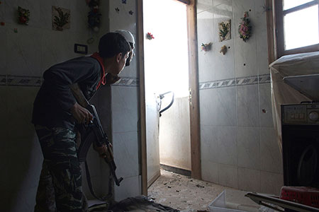  Un jeune combattant de l'Armée syrienne libre, âgé de 14 ans, prend position à l'intérieur d'une maison à Deir al-Zor, dans l'est de la Syrie, en juillet 2014